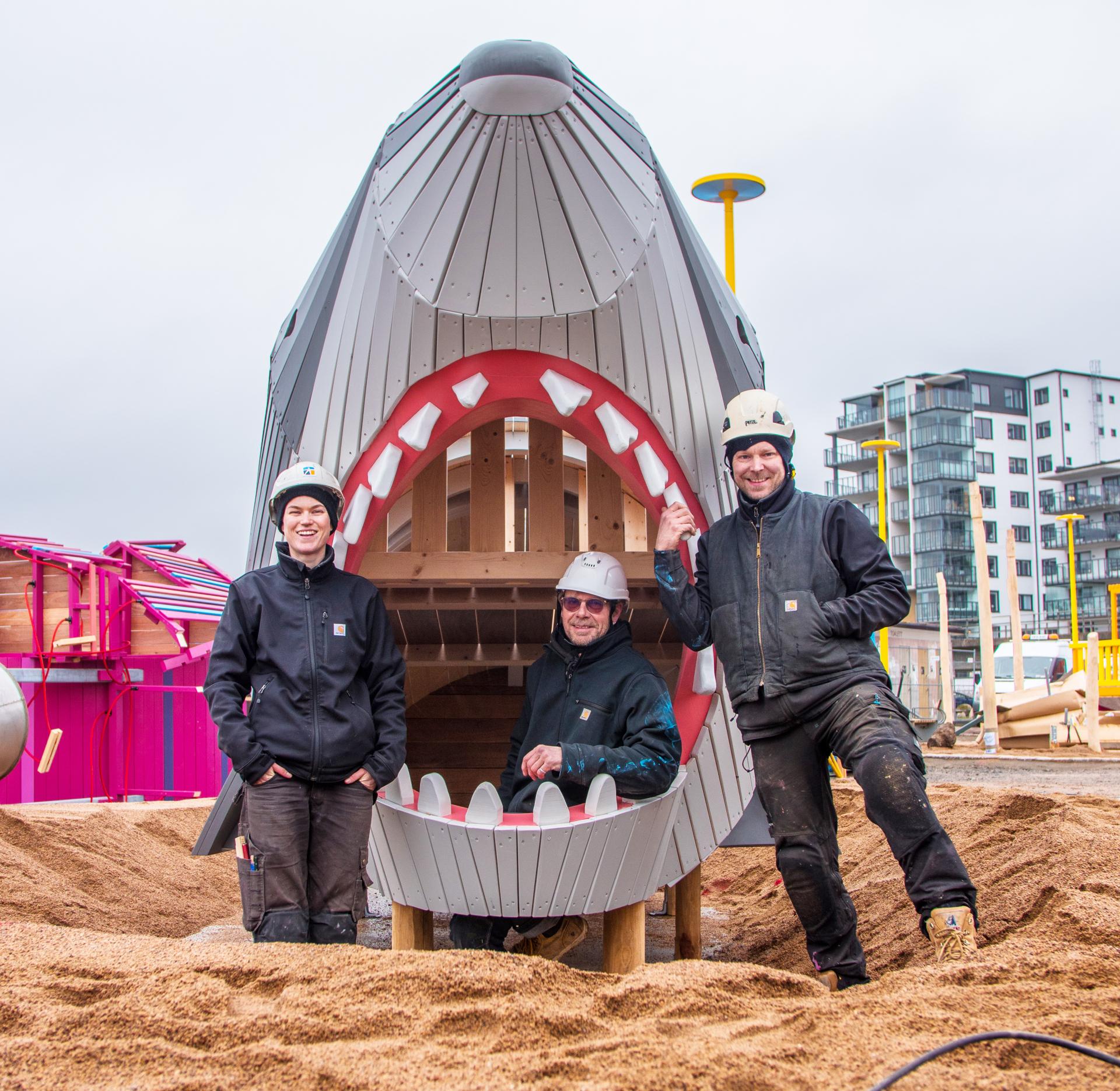 MONSTRUM team posing with wooden shark at playground installation