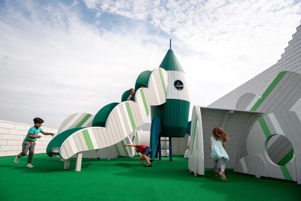 Rocket playground with slide and cloud elements, children playing, LEGO House