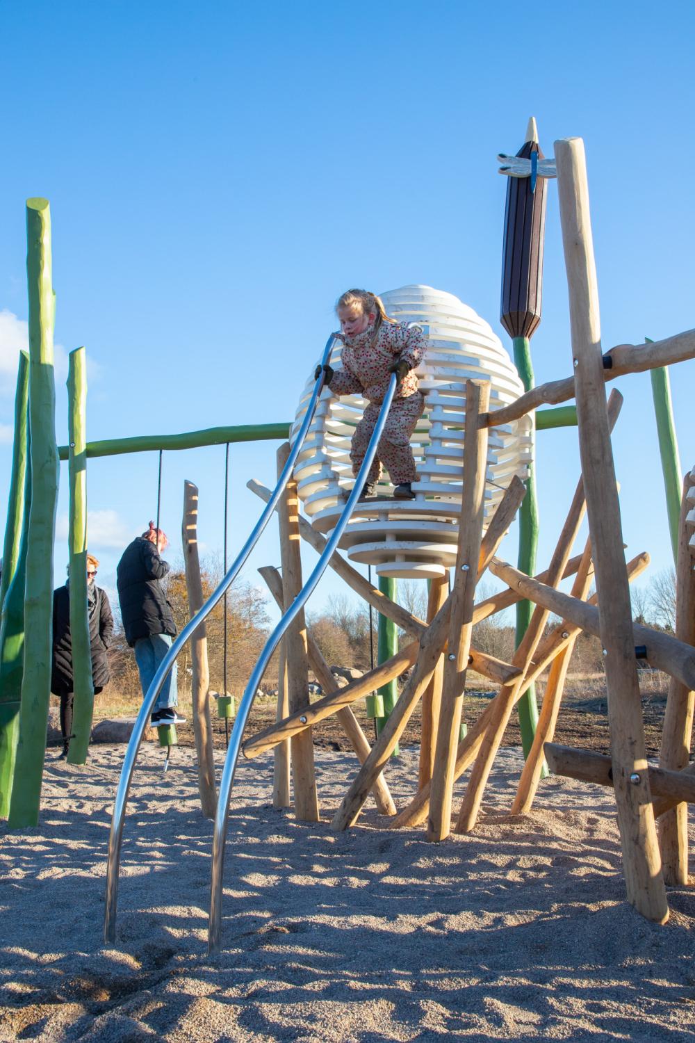 Girl about to slide down steel poles at playground