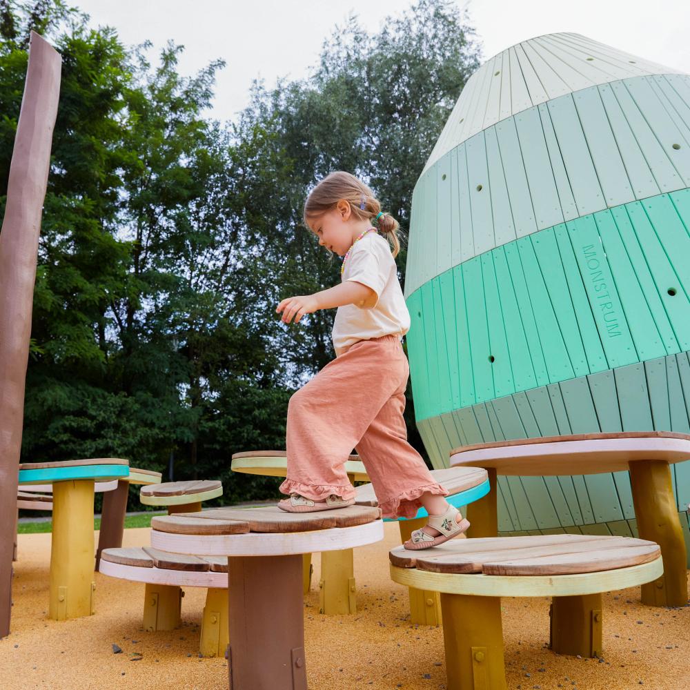 Girl jumping and playing on wooden MONSTRUM playground